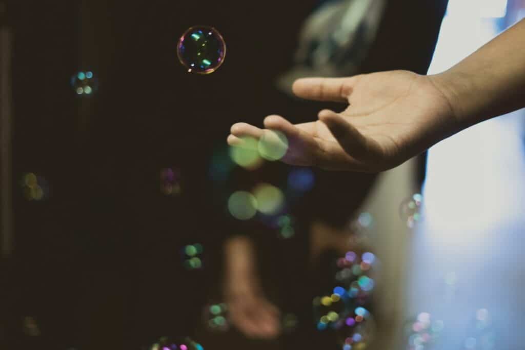 Hand die uitreikt naar zeepbellen. Dit is symbool voor de gevoeligheid van ons lichaam waarmee we emoties ervaren.